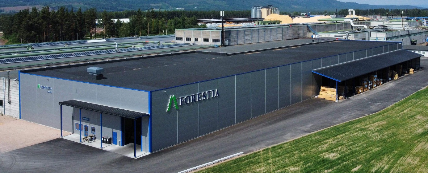 Forestia Logistikksenter. Stor avlang bygning med grått platebelagt eksteriør og flatt tak. Blå dører og lister. Stor Forestia logo på siden av bygget.